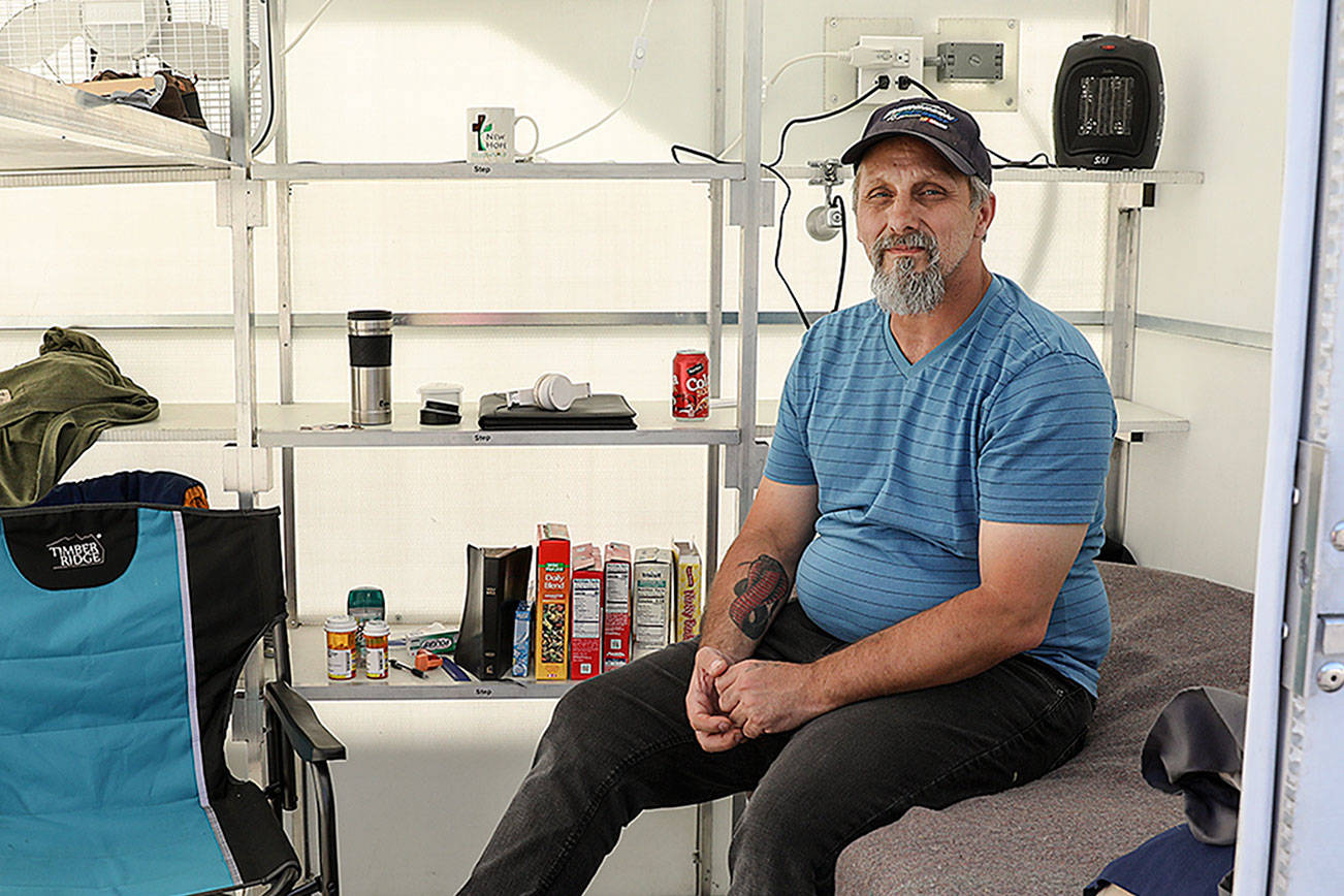 Roger Evans is working to bring a tiny home village for people experiencing homelessness to the Monroe church New Hope Fellowship. He sits in a demo unit that was brought to church grounds recently. (Lizz Giordano / The Herald)