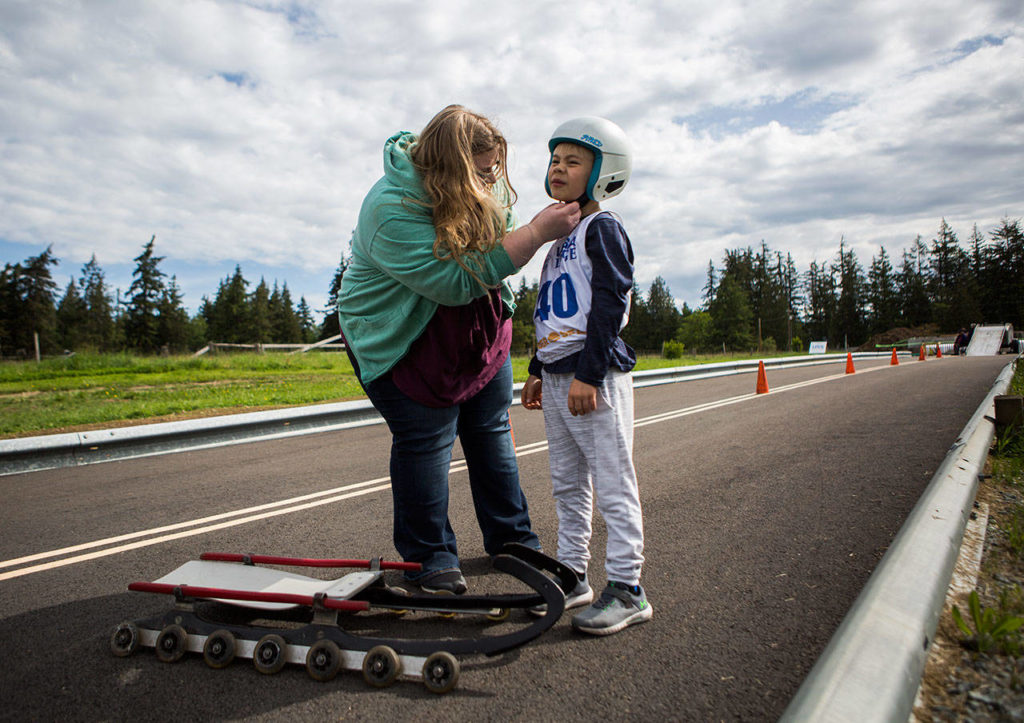 Caden Delaney gets help adjusting his helmet during the USA Luge Slider Search program Sunday at Arrowhead Ranch on Camano Island. (Olivia Vanni / The Herald)
