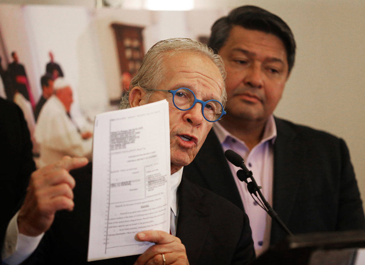 Attorney Jeff Anderson (left), accompanied by Manuel Vega, who says he was sexually abused by a priest, describes Vega’s lawsuit against the Vatican at a news conference in Los Angeles on Oct. 4. Several people, including Vega, are planning to sue the Vatican on Tuesday and are demanding to know the names of thousands of predator priests they claim have been kept secret by the Holy See, according to Anderson. (AP Photo/Reed Saxon, File)