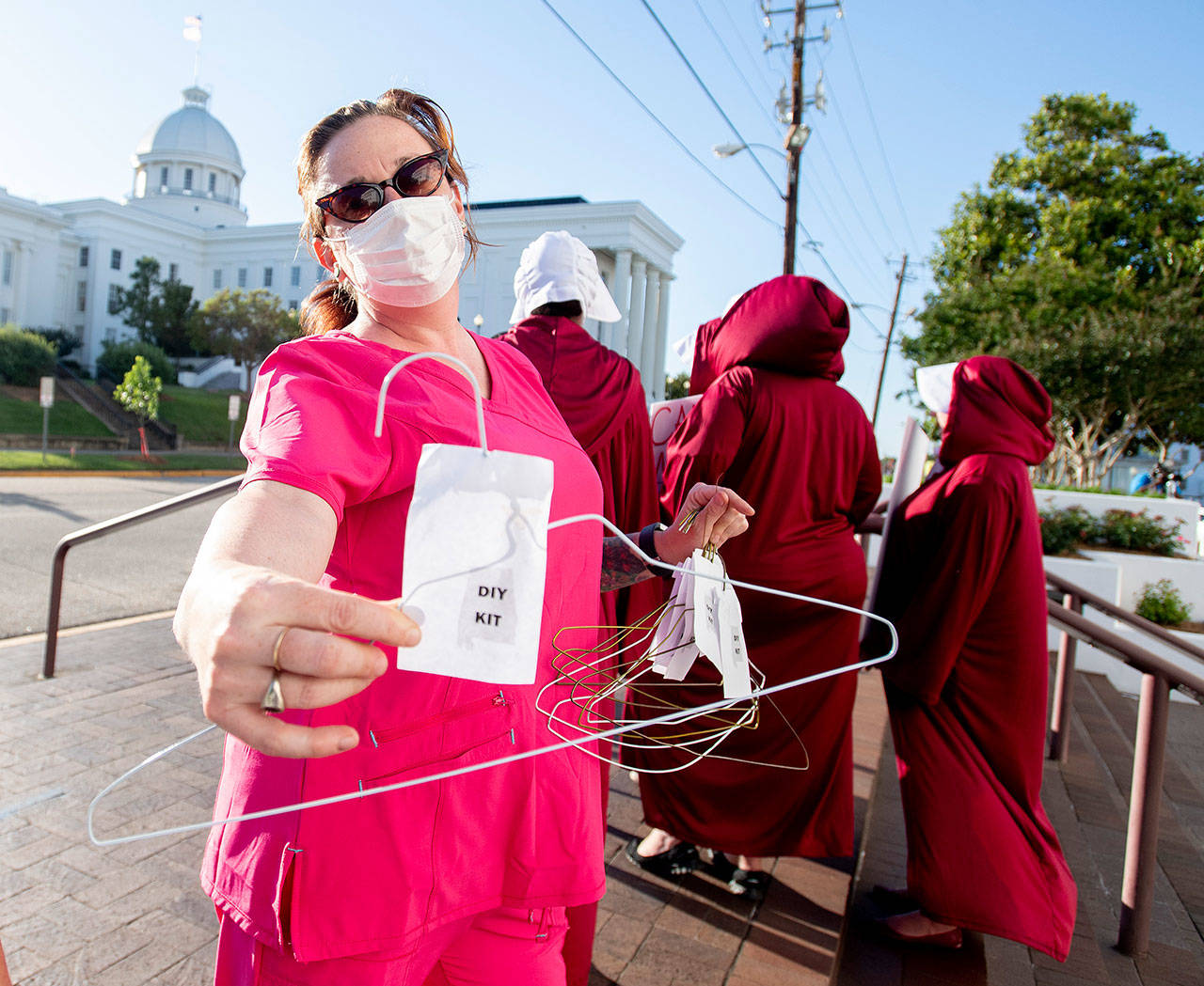 Laura Stiller hands out coat hangers as she talks about illegal abortions Tuesday during a rally against HB314, the near-total ban on abortion bill, outside of the Alabama State House in Montgomery. (Mickey Welsh/The Montgomery Advertiser via AP)