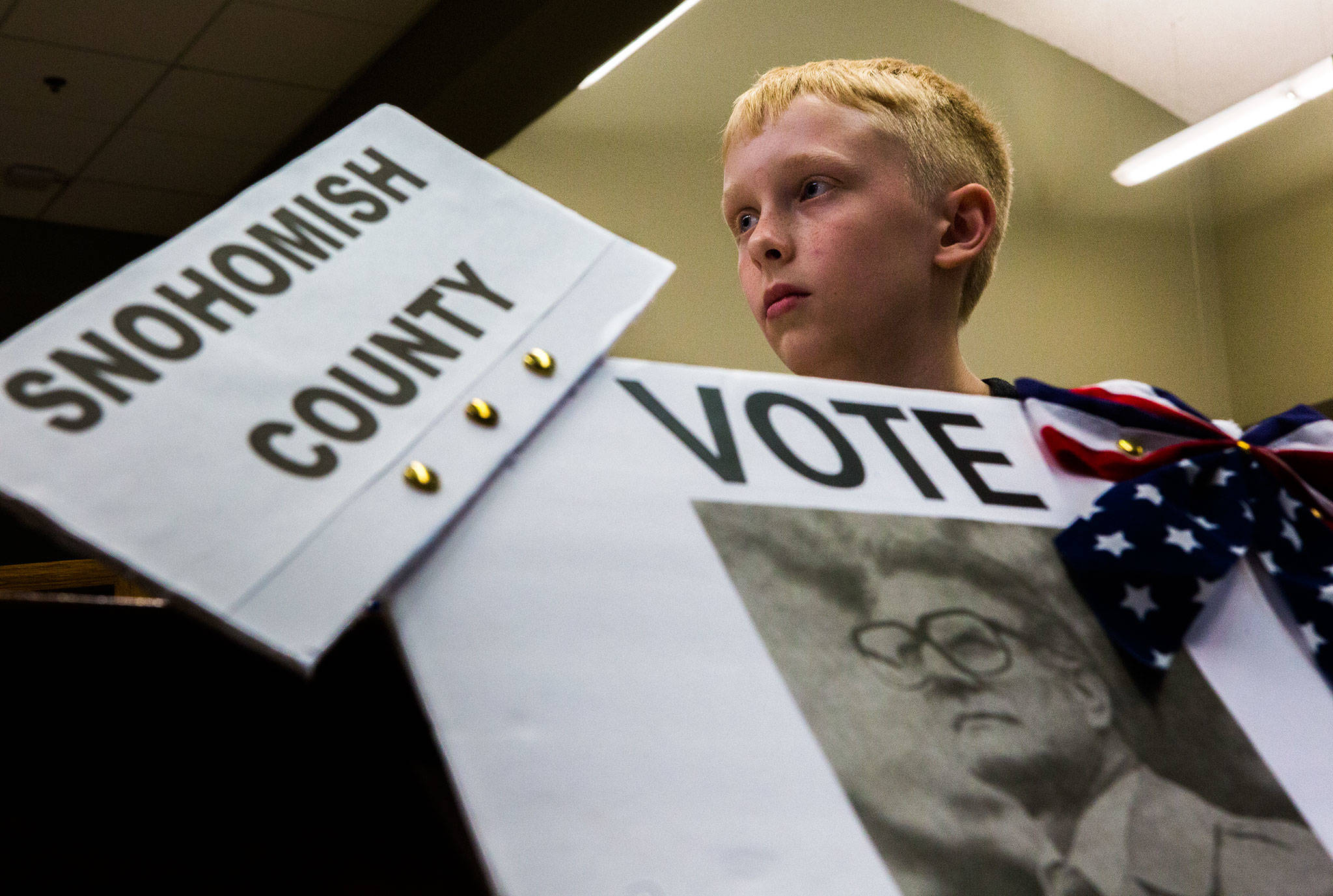 Spencer Armstrong, 11, sits next to a poster he made with Willis D. Tucker’s photo at the Snohomish Library. He chose Tucker as the subject of his school research project. (Olivia Vanni / The Herald)