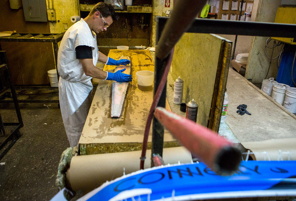 Nick Hoyt spreads resin over a water ski at Connelly Skis in Lynnwood. (Olivia Vanni / The Herald) 
