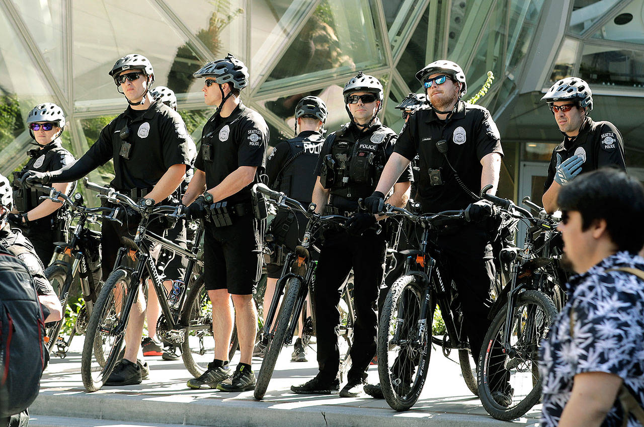 Seattle Police officers on bikes stand in front of the Amazon Spheres during a march for immigrant and workers rights on May Day in downtown Seattle. A federal judge has found that a portion of Seattle’s contract with its biggest police union threatens to undermine public confidence in a seven-year-old reform agreement between the city and the Department of Justice. U.S. District Judge Robart said Wednesday that the city must fix deficiencies in the closed-door appeal process. (AP Photo/Ted S. Warren, File)