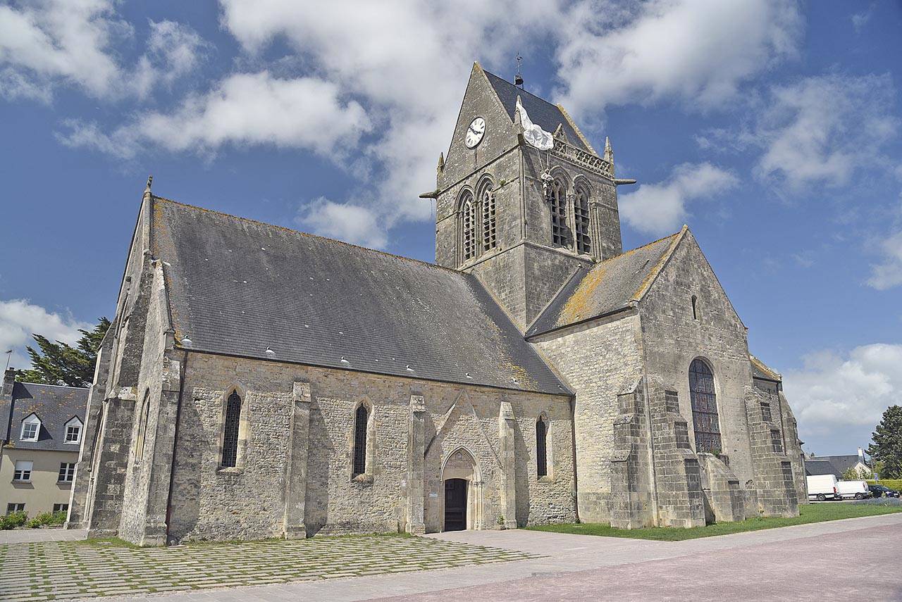During the D-Day invasion, off-course American paratroopers landed in the middle of the village of Ste-Mere Eglise. One paratrooper’s chute caught on a church spire, which the village commemorates today with a mannequin dangling on the church. (Rick Steves’ Europe)
