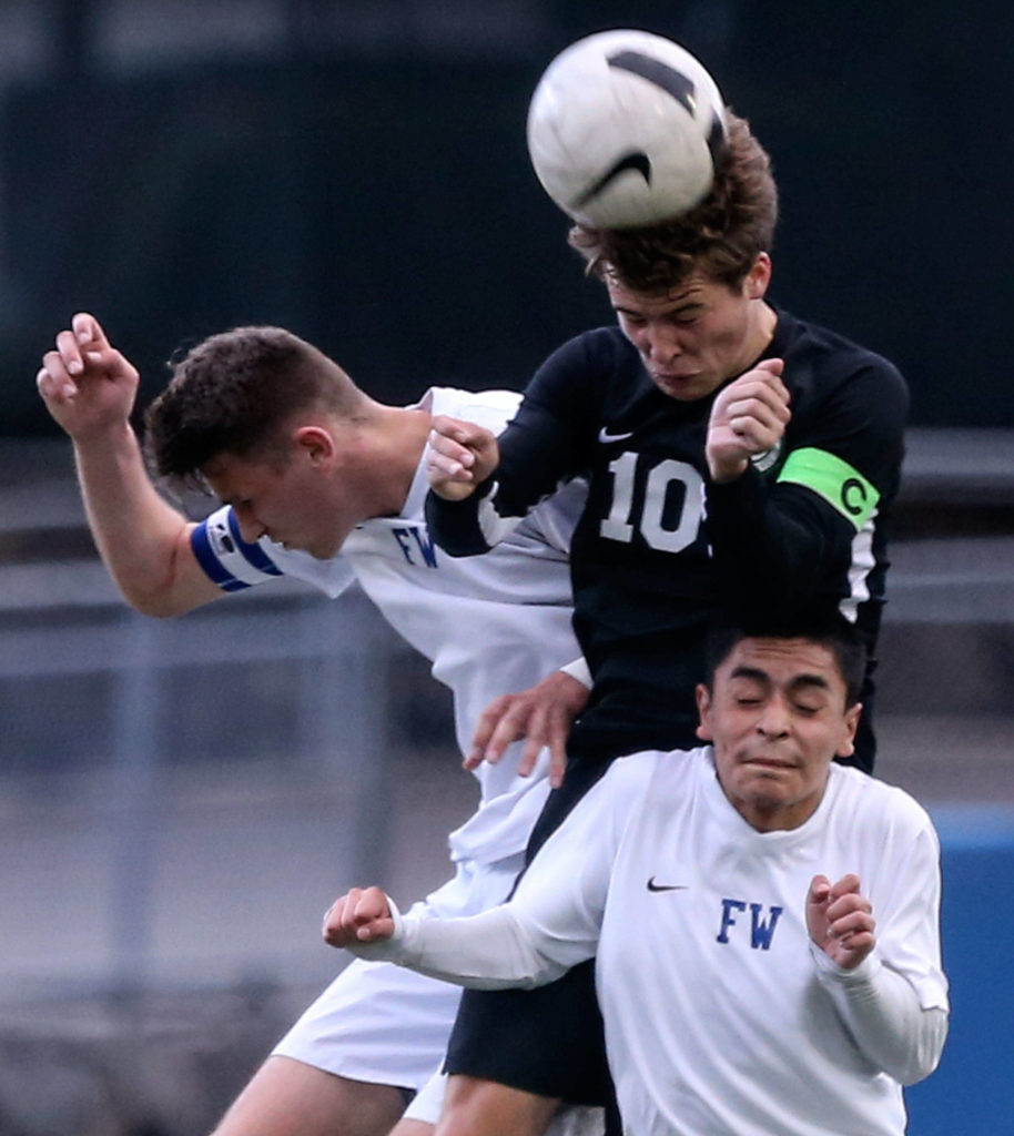 Jackson’s Jacob Williams out-jumps Federal Way’s Zane Baumgardt (left) and Carlos Quijada for a header during a 4A state soccer match on May 17, 2019, at Everett Memorial Stadium. The Timberwolves won 2-1. (Kevin Clark / The Herald)
