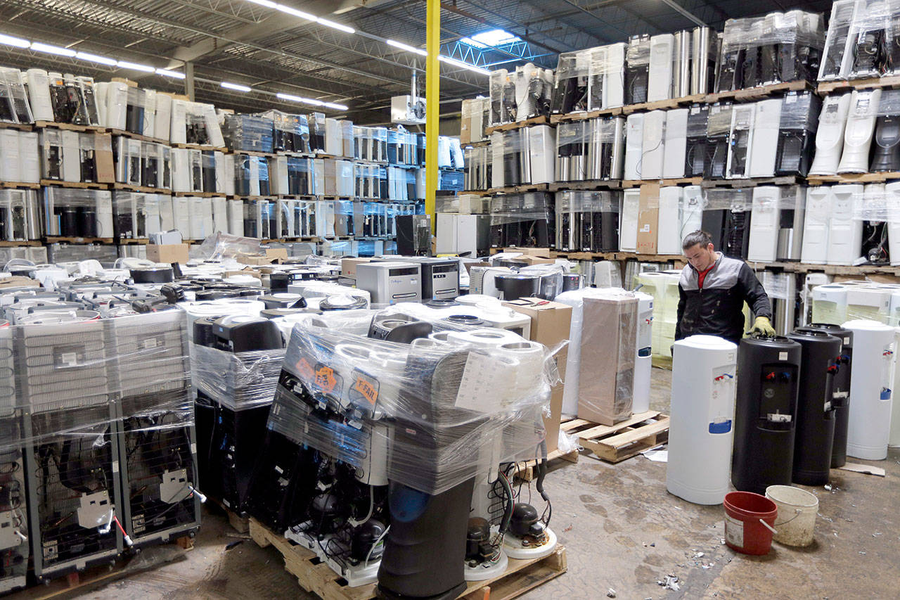 In this May 7, 2019 photo, water coolers are stacked and ready to be broken down into parts for recycling at a GDB International warehouse in Monmouth Junction, New Jersey. China’s decision to restrict scrap imports created big challenges for U.S. recycling programs last year. But it has also spurred investment in plants that process recyclables no longer being shipped overseas. (AP Photo/Seth Wenig)