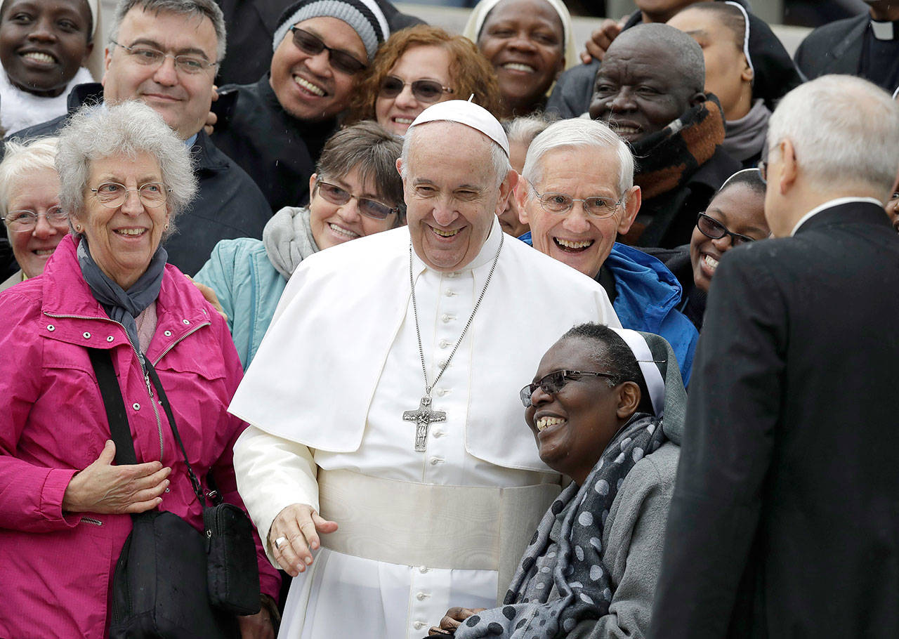 Pope Francis shares a laugh with a group of faithful as he poses for a family photo, at the end of his weekly general audience in St. Peter’s Square, at the Vatican on Wednesday. (AP Photo/Andrew Medichini)