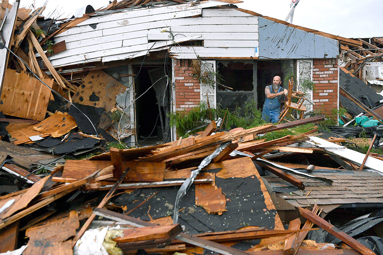 Wesley Mantooth lifts a wooden chair out a window of the home of his father, Robert, in Abilene, Texas, on Saturday. Many residents said a tornado struck in the early morning hours. (Ronald W. Erdrich/The Abilene Reporter-News via AP)