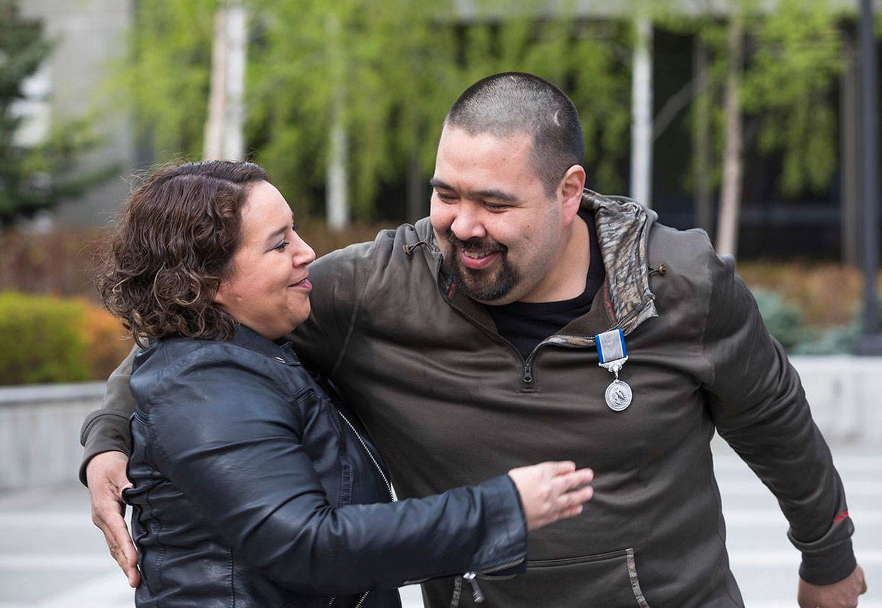 Nome Magistrate Judge Pamela Smith gets a hug from her friend, George “Radar” Lambert after Lambert was given a Silver Lifesaving Medal at the Atwood Building courtyard in Anchorage, Alaska, on Saturday. Lambert was awarded the medal by the U.S. Coast Guard for saving Smith from drowning in Kotzebue in 1998, when he was 10 and she was 12. (Loren Holmes/Anchorage Daily News via AP)