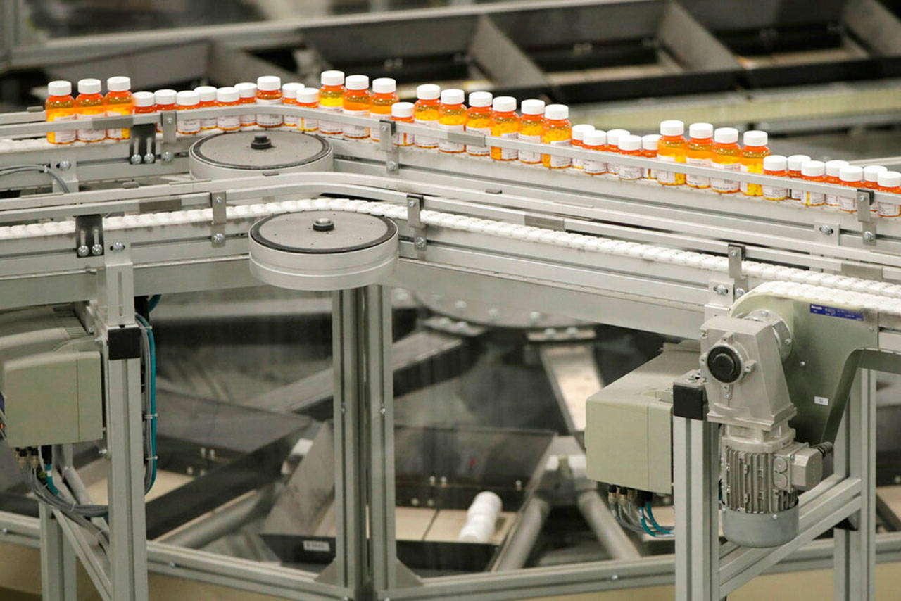 Bottles of prescription drugs ride a conveyor belt at a pharmacy warehouse in Florence, N.J., in July, 2018. Recent actions at the state and national level are increasing transparency for drug prices. (Julio Cortez / Associated Press file photo)