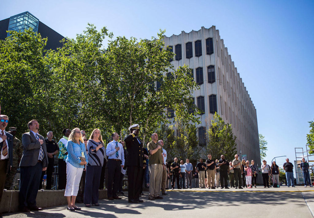 People in a large crowd hold their hands over their hearts while the national anthem is sung at a veteran’s memorial commissioning ceremony Thursday near the Snohomish County courthouse. (Olivia Vanni / The Herald)
