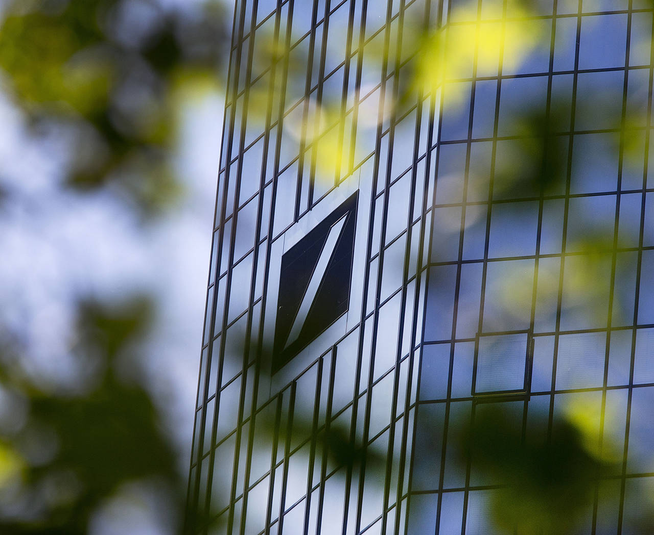 The headquarters of Deutsche Bank is seen through green leaves in Frankfurt, Germany on April 30. (AP Photo/Michael Probst, file)