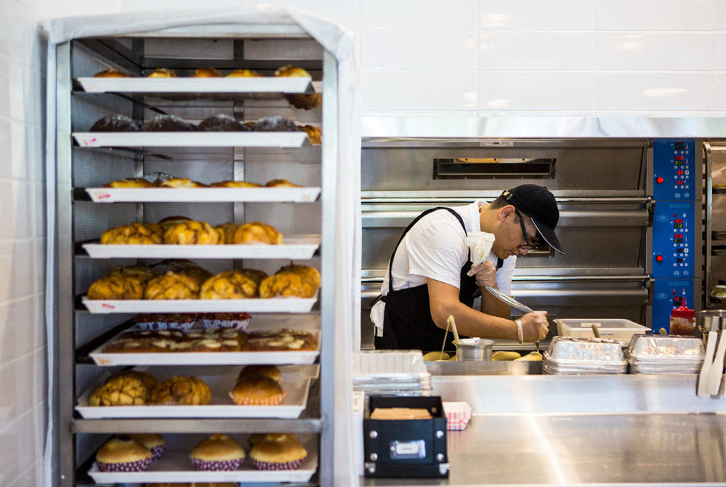 Baker Abel Calderon-Cardozo decorates fresh pastries at 85°C Bakery Cafe on May 22 in Edmonds. (Olivia Vanni / The Herald)
