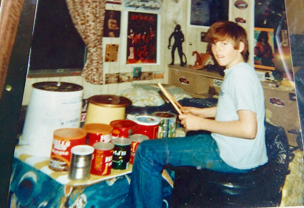 Michael Peterson at age 12 in his Sultan home with the drum set he made of coffee cans on a plywood board that he filled with water to get different sounds. He became a professional drummer. (Submitted photo)
