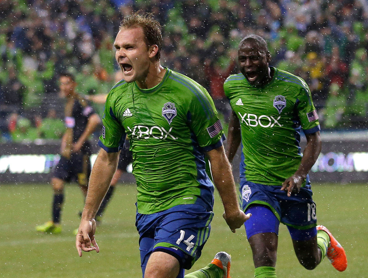 The Sounders’ Chad Marshall (14) celebrates with teammate Djimi Traore after Marshall scored the game-winning goal in a match against the Union in 2014 in Seattle. Marshall announced his retirement on Wednesday due to injury. (AP Photo / Ted S. Warren)