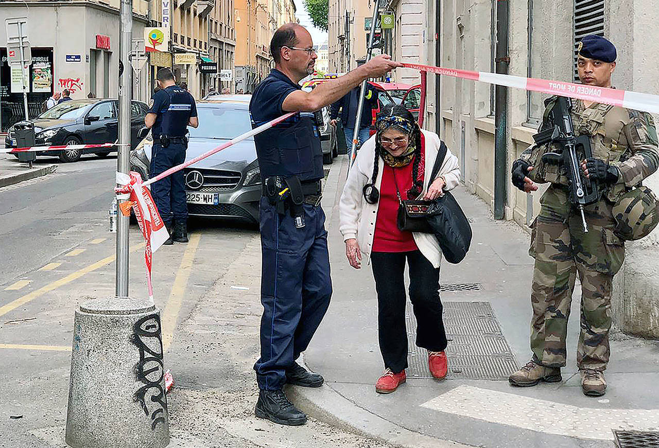 A police officer lets an elderly woman leave the area while soldiers secure the access near the site of a suspected bomb attack in central Lyon on Friday. (AP Photo/Sebastien Erome)