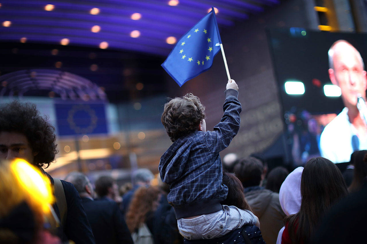 A young boy waves an EU flag as he watches a giant screen television outside the European Parliament in Brusselson Sunday. From Germany and France to Cyprus and Estonia, voters from 21 nations went to the polls Sunday in the final day of a crucial European Parliament election that could see major gains by the far-right, nationalist and populist movements that are on the rise across much of the continent. (AP Photo/Francisco Seco)