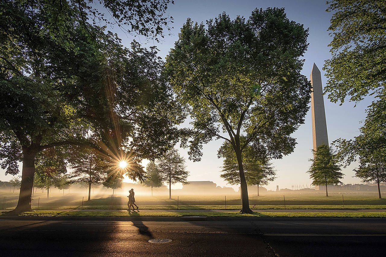 Early morning runners pass the Washington Monument as they run across the National Mall at daybreak on May 26 in Washington. (AP Photo/J. David Ake)