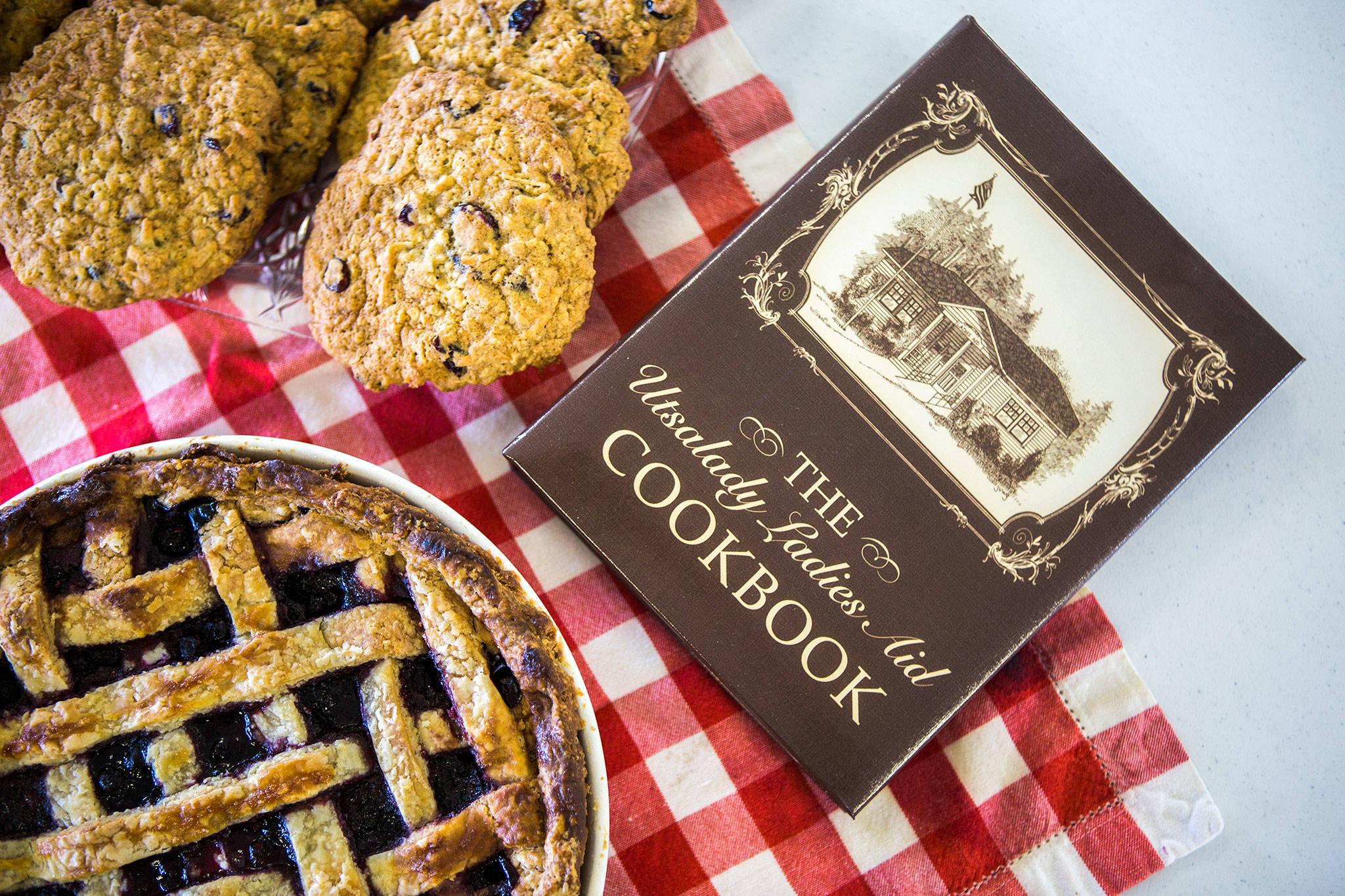 The Utsalady Ladies Aid Cookbook sits next to a tray of cookies and a pie, both recipes from the group’s cookbook. (Olivia Vanni / The Herald)