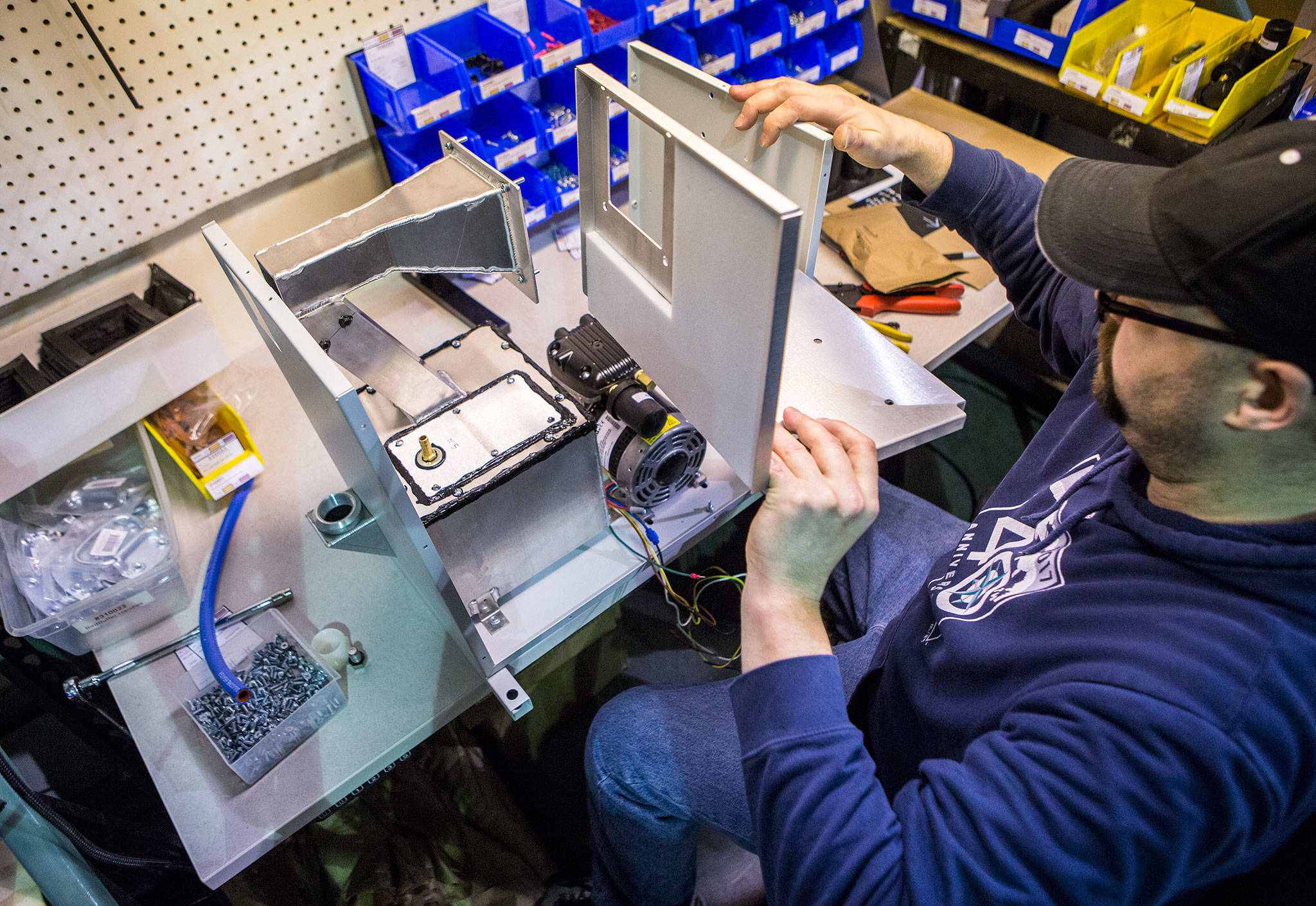 BirdBuffer employee Michael Ludwig assembles one of the company’s repellant-dispensing machines in Everett. (Olivia Vanni / The Herald)