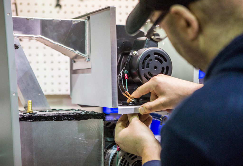 Employee Michael Ludwig secures the mist blower to the upper part of a BirdBuffer machine. (Olivia Vanni / The Herald) 
