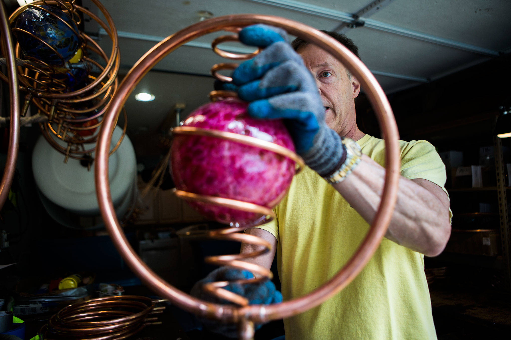 Steve Hopkins, owner of Hoppy’s Garden Art, installs a blown-glass globe in a sprinkler at his home workshop in Bothell. (Olivia Vanni / The Herald)