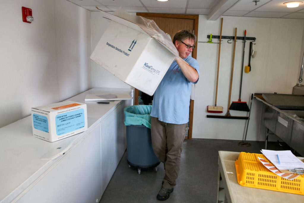 Scott Albrecht unpacks samples at the labs of NSF International in Everett. (Kevin Clark / The Herald)
