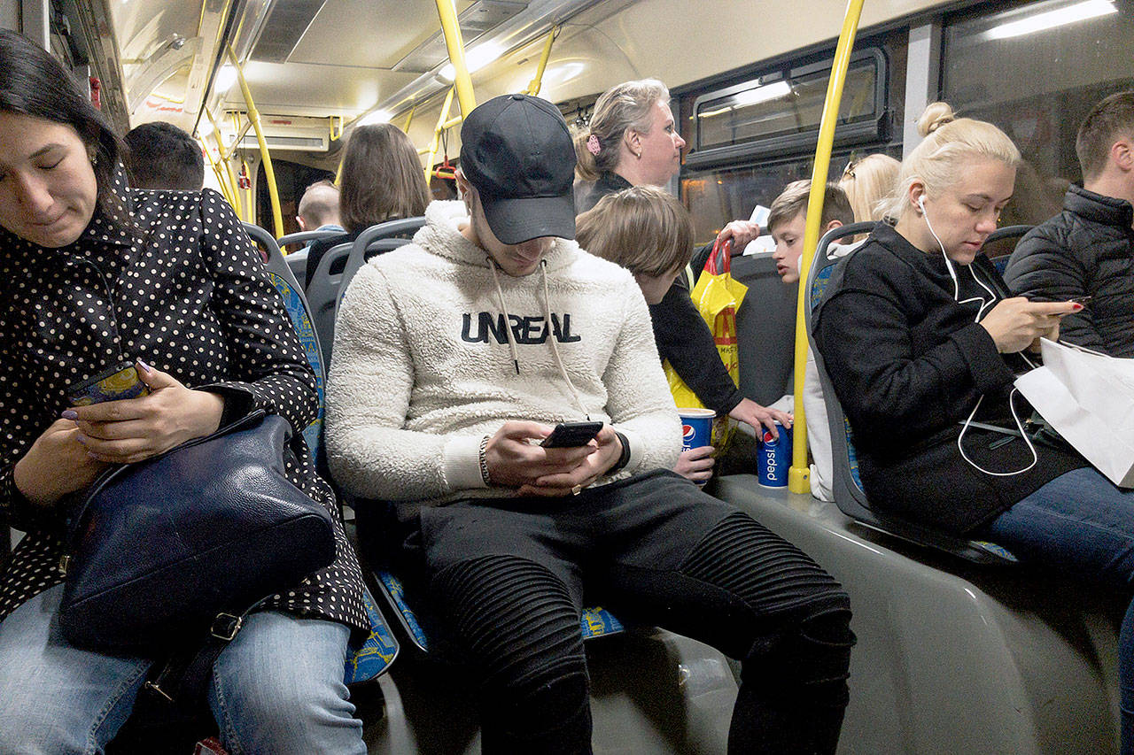 Passengers look at their smartphones as they ride a bus in Moscow, Russia. (AP Photo/Alexander Zemlianichenko)