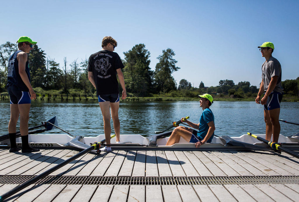 Dylan Stengel (left) and William Sweeney talk with Ethan Miedema (seated) as they get into their boat before a May 31 Everet Rowing Association practice on the Snohomish River in Everett. (Olivia Vanni / The Herald)

