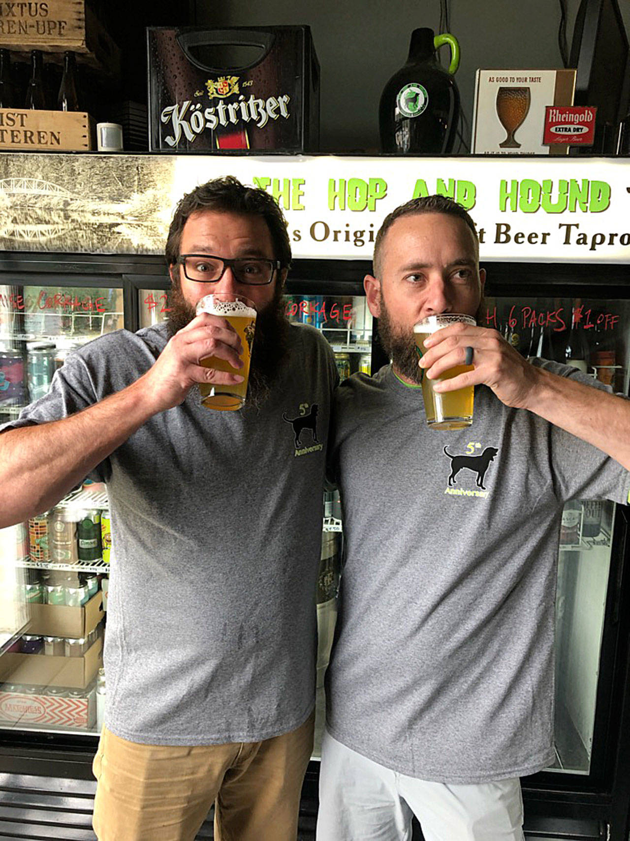 Bothell’s The Hop and Hound owner Eric Schaffer (left) and Varietal Brewing co-owner David Paulson tip back a pint of Hazedog Millionaire, a collaboration between Varietal and Wandering Hop Brewing for The Hop and Hound’s fifth anniversary celebration this weekend. (The Hop and Hound)