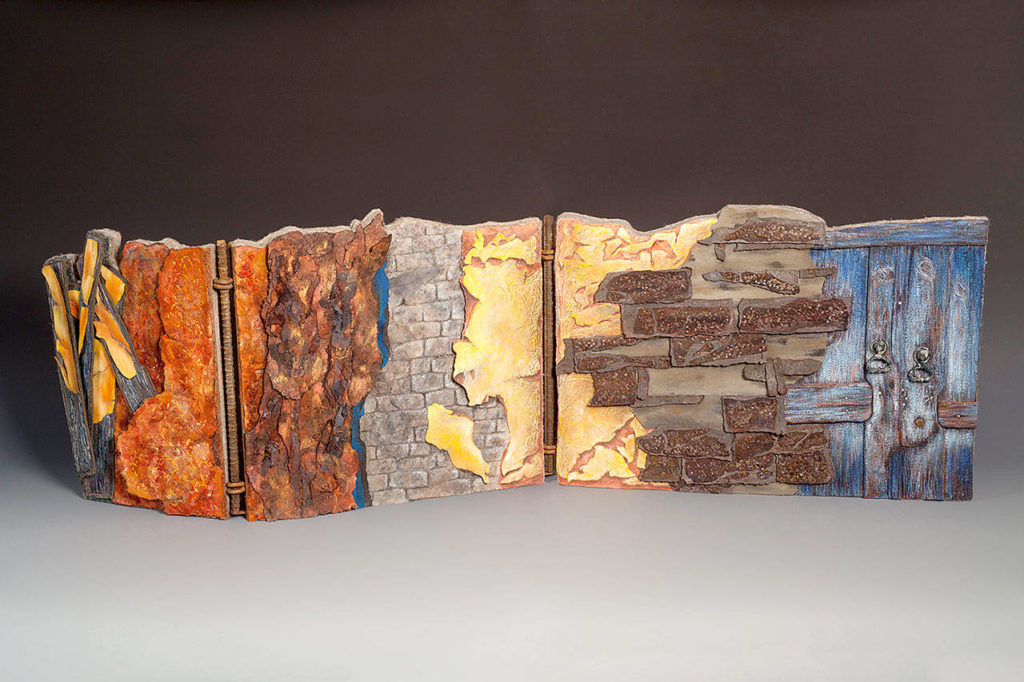 Terri Shinn’s “Time Crumbles Things” was inspired by photos of structural decay. She made an 18-inch-tall and 56-inch-long wall of fabric, felt, car-headliner padding, threads, texture mediums, plywood, rebar, hinges and door knockers.
