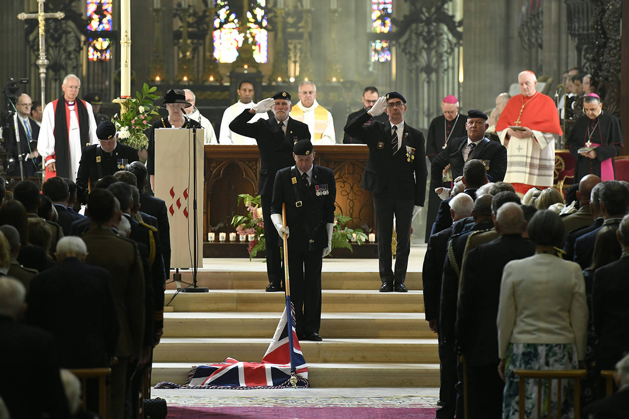 Bishop Jean-Claude Boulanger (right) looks at veterans lowering the Union Jack as they pay their respect during a ceremony at the Cathedral of Bayeux, Normandy, on Thursday as part of D-Day commemorations marking the 75th anniversary of the World War II Allied landings in Normandy. (Bertrand Guay/ POOL via AP)