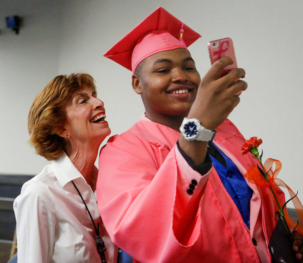 Terrence Barton, 20, who stood out in a pink cap and gown, takes a selfie with Laura Wilson, who has been his mentor since he was 12. (Dan Bates / The Herald)
