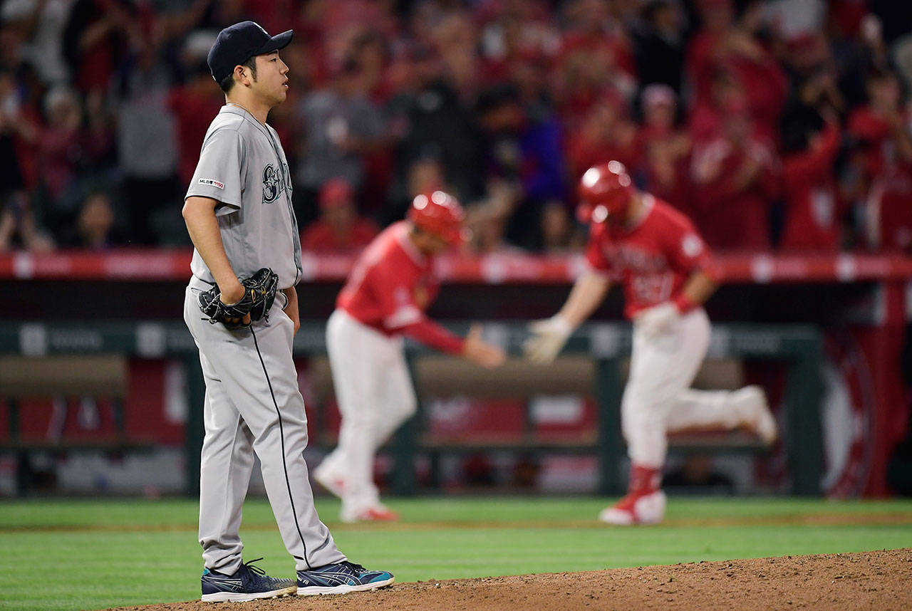 Seattle Mariners starting pitcher Yusei Kikuchi waits as Los Angeles Angels’ Mike Trout (right) is congratulated by third base coach Mike Gallego after hitting a solo home run during the fourth inning of a baseball game Saturday, June 8, 2019, in Anaheim, Calif. (AP Photo/Mark J. Terrill)