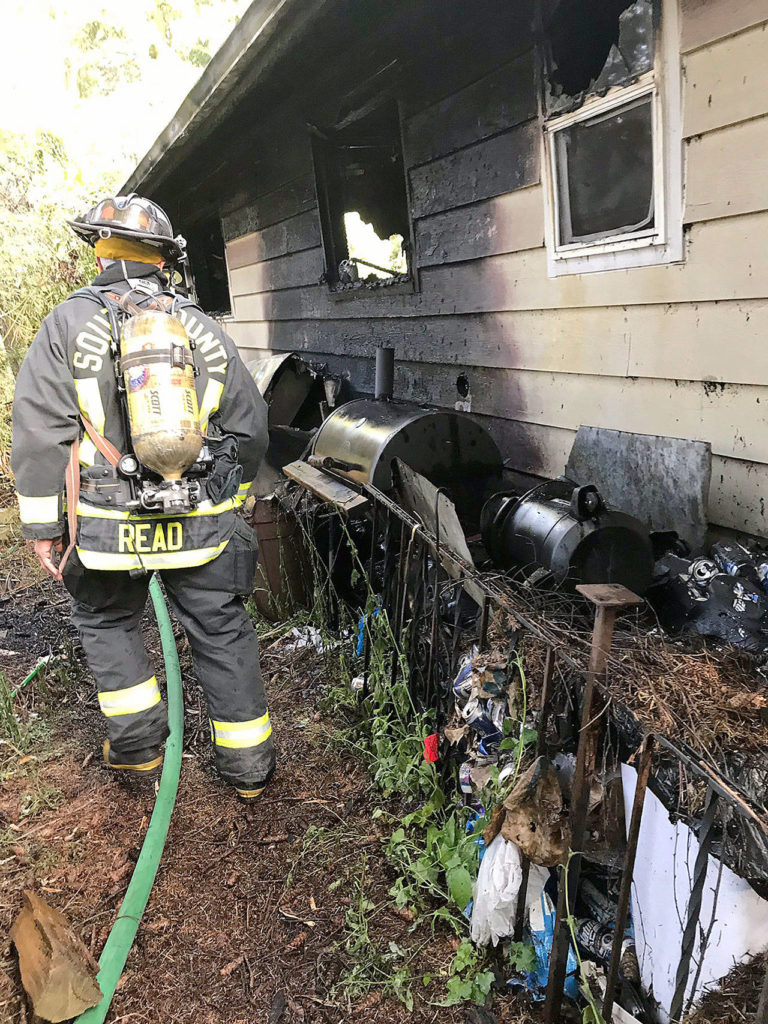 A firefighter evaluates the outside of a home after fire damaged it Monday morning in Lynnwood. (South Snohomish County Fire)
