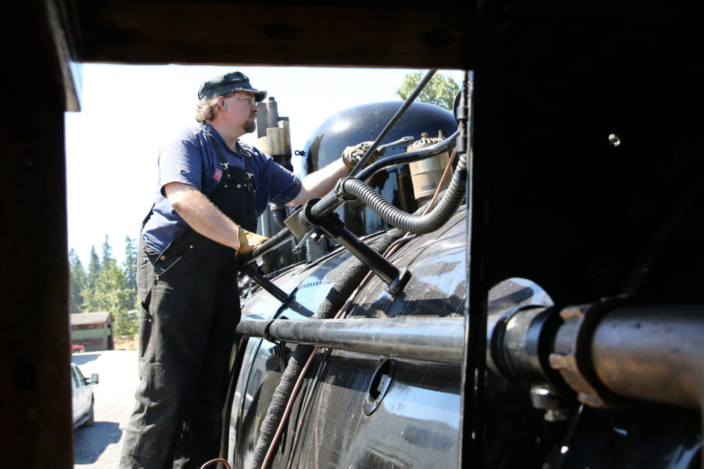 Steve Butler calibrates the steam release on the restored engine at The Newell Corporation in Arlington on June 11. (Kevin Clark / The Herald)
