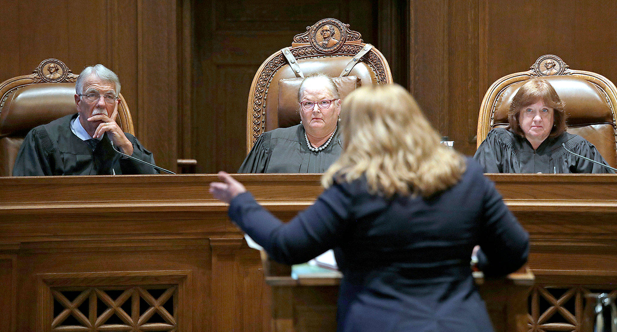 From left, Justice Charles W. Johnson, Chief Justice Mary E. Fairhurst and Justice Barbara A. Madsen listen to Michele Earl-Hubbard, the attorney for a media coalition, during a hearing before the Washington Supreme Court on Tuesday in Olympia. (AP Photo/Elaine Thompson)