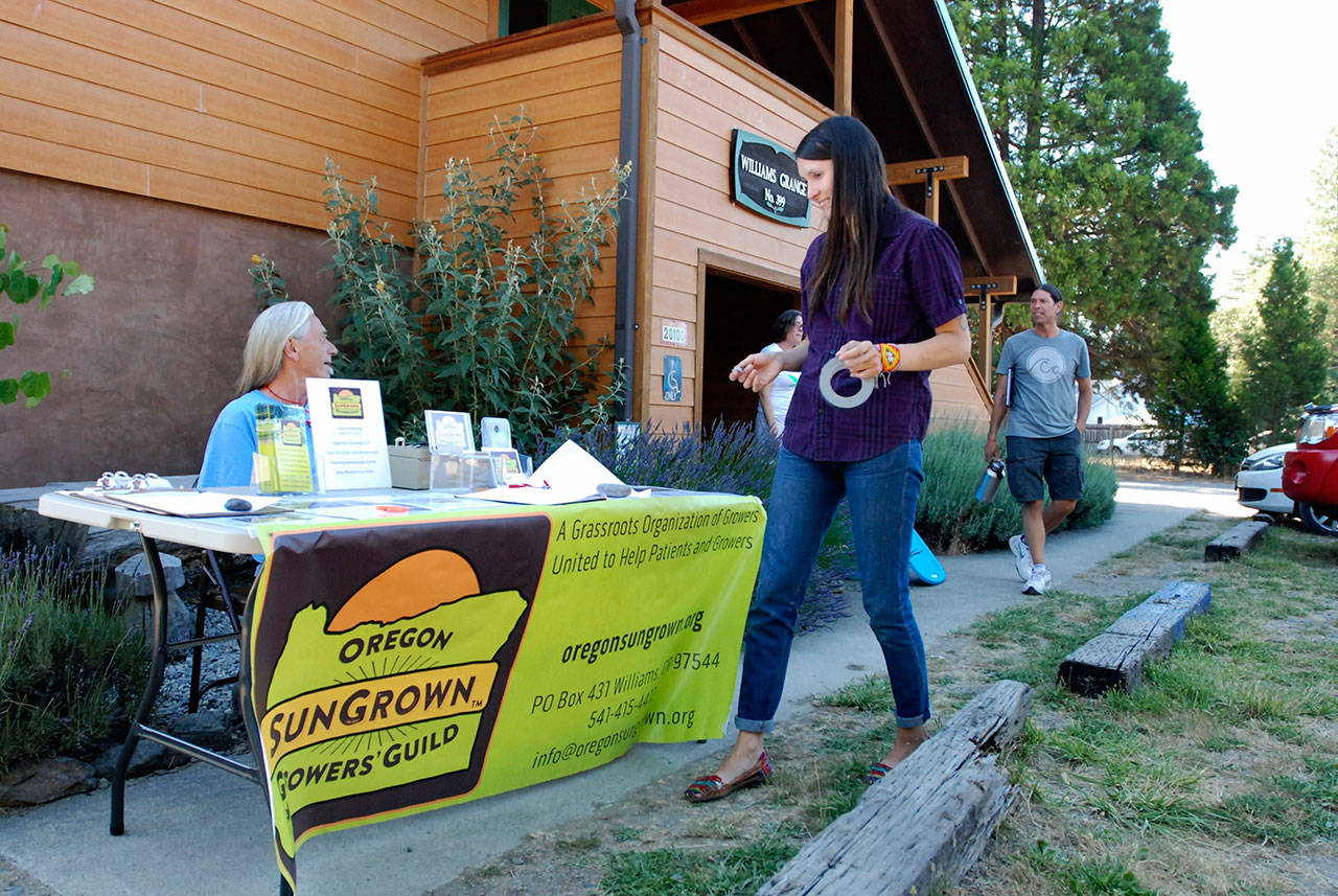 Gina Erdmann, director of the Oregon SunGrown Growers’ Guild, sets up a sign-in table for the monthly meeting of marijuana growers in the old Williams Grange in Williams, Oregon, on June 25, 2015. Oregon’s Legislature on Tuesday passed a bill that empowers the governor to enter into agreements with other states for the interstate transfer of marijuana, once the federal government allows it. (AP Photo/Jeff Barnard, File)