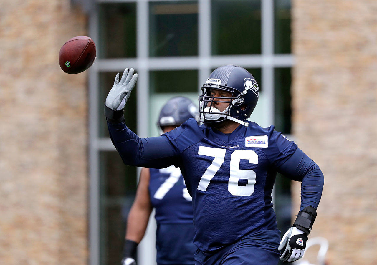 The Seahawks’ Duane Brown tips away a football during a practice on May 21, 2019, in Renton. (AP Photo/Elaine Thompson)