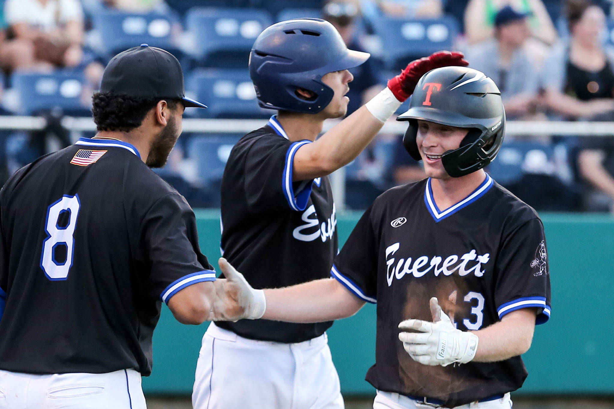 Austin Hauck (right) celebrates with Riley Parker (center) and Koby Blunt (left) after scoring a run the 6th inning against the AquaSox in the Everett Cup on June 12, 2019, at Funko Field at Everett Memorial Stadium. (Kevin Clark / The Herald)