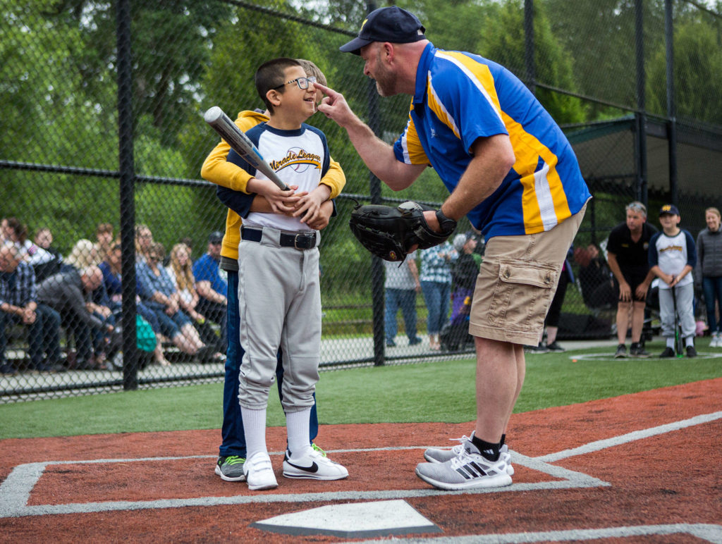 Angelo Chavez, 12, who has participated in Miracle League for five years, smiles as coach Don Purvis taps his nose before his at-bat. (Olivia Vanni / The Herald)

