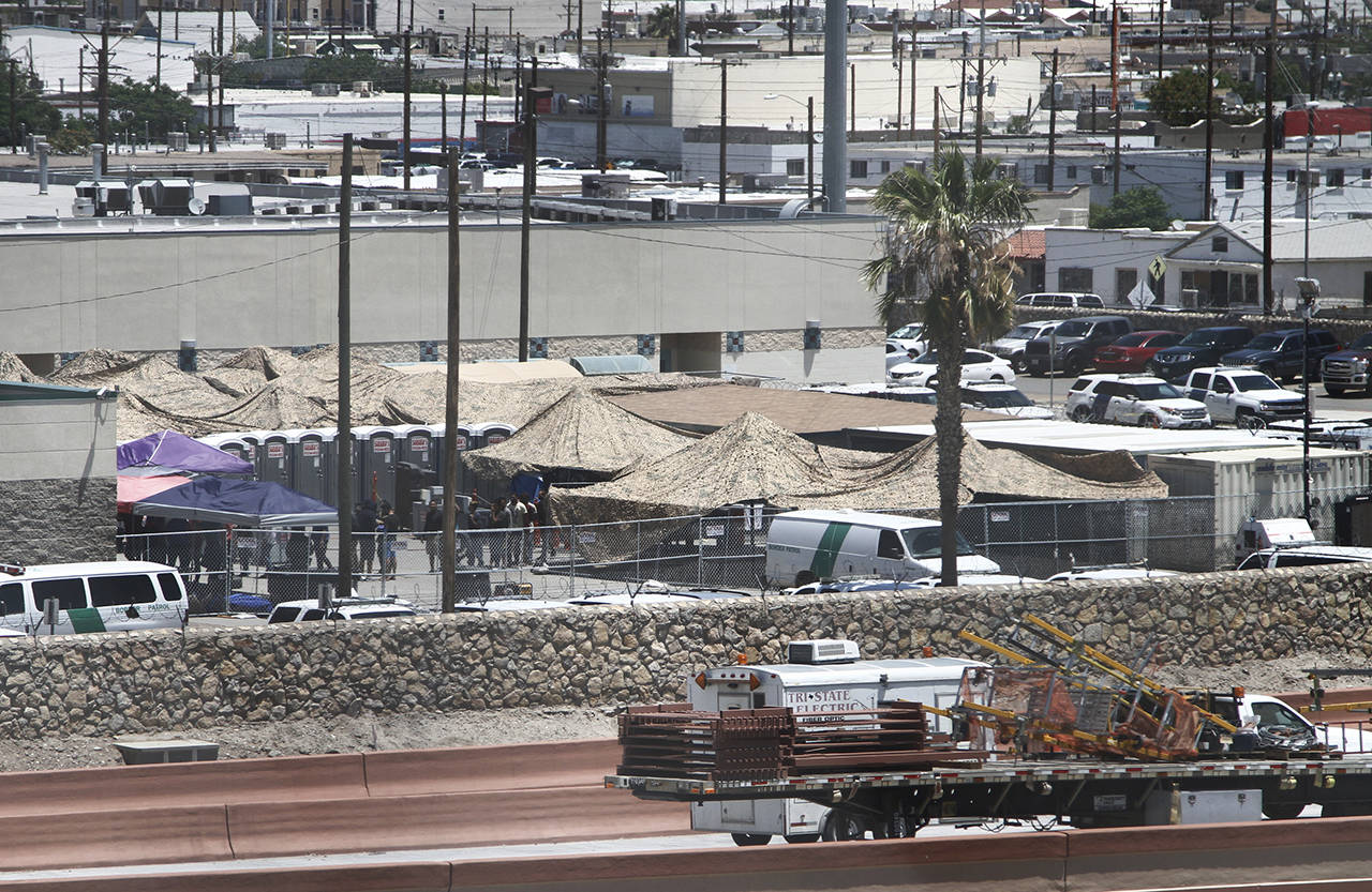 In this June 12 photo, migrants are seen within a fenced-off area inside a temporary outdoor encampment where they’re waiting to be processed in El Paso, Texas. (AP Photo/Cedar Attanasio)