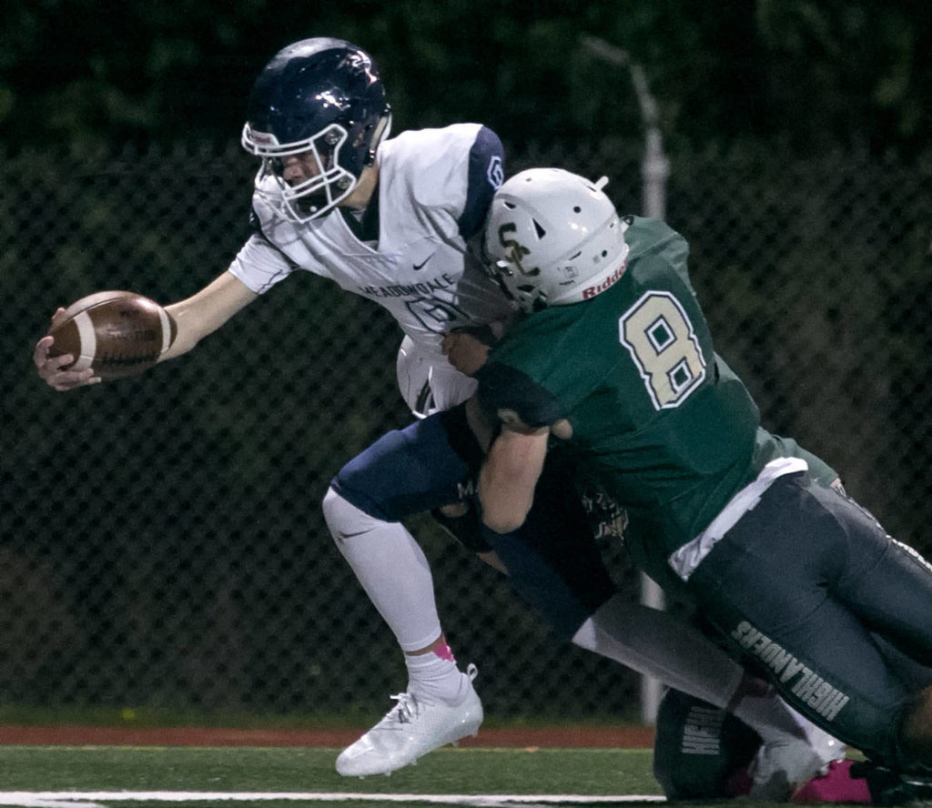 Meadowdale’s Hunter Moen reaches for extra yardage with Shorecrest’s Gavin McFarlane tackling at Shoreline Stadium on Oct. 12, 2018. (Kevin Clark / The Herald)
