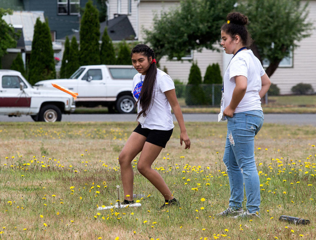 Haller Middle School student Elizabeth Robles stomps on a plastic bottle, sending a rocket into the air, as Adriana Rodriquez watches the trajectory on Tuesday in Arlington. (Andy Bronson / The Herald)
