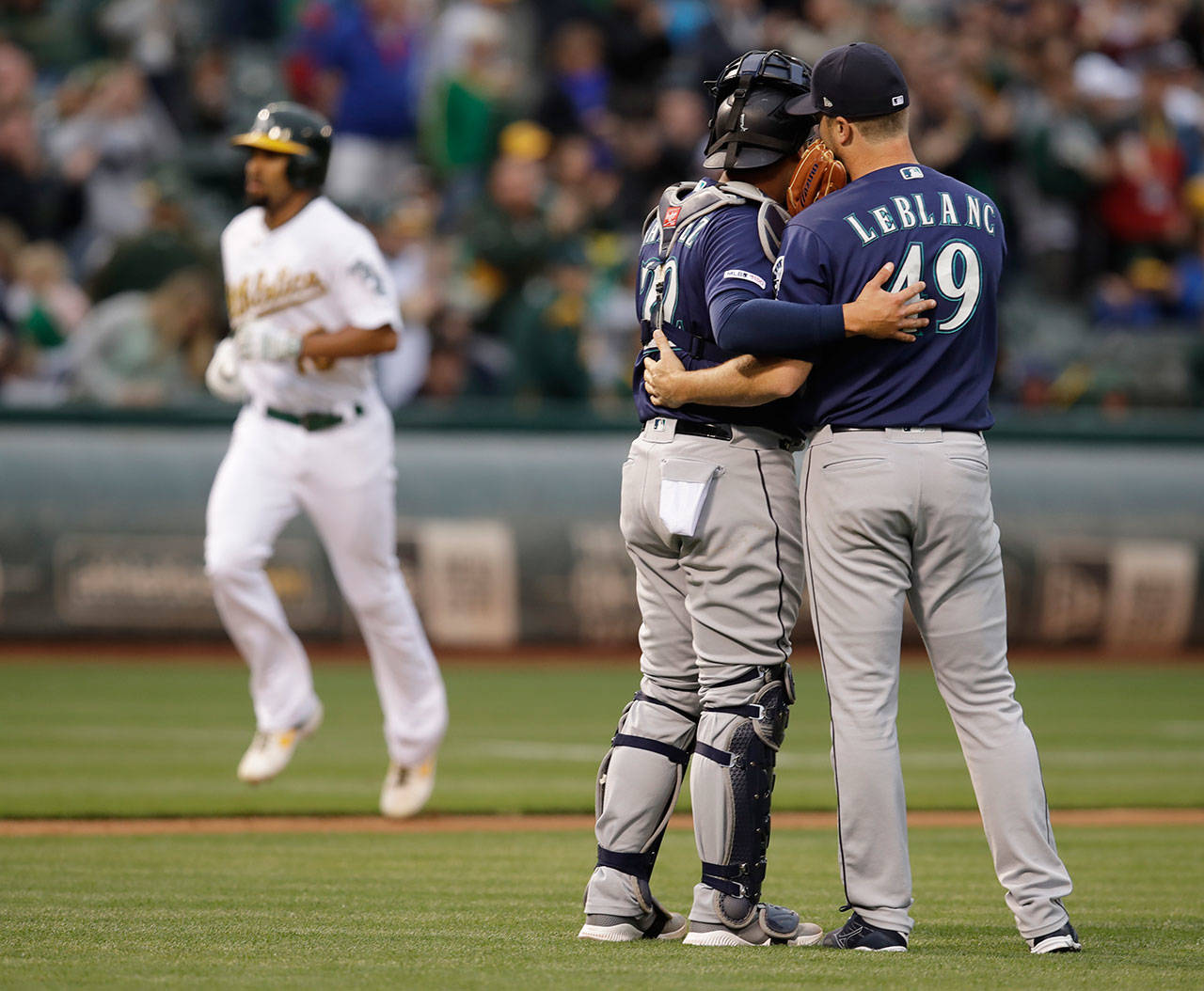 Mariners pitcher Wade LeBlanc (right) speaks with catcher Omar Narvaez as they wait for the Athletics’ Marcus Semien (back left) to run the bases after hitting a home run in the second inning of a game on June 15, 2019, in Oakland, Calif. (AP Photo/Ben Margot)