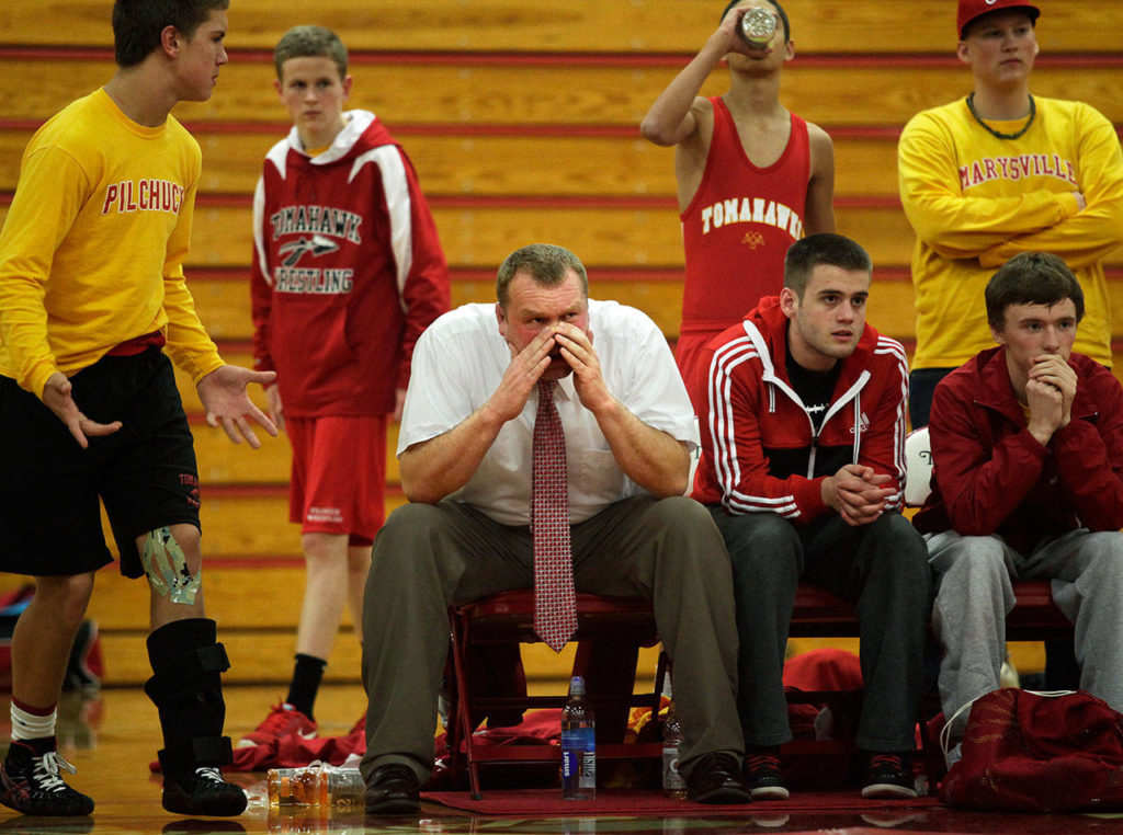 Marysville-Pilchuck head wrestling coach Craig Iversen, center, cheers on his team Dec. 12, 2012 during a nonconference meet against Arlington High School, then coached by his father, Rick Iversen. (Annie Mulligan / Herald file) 
