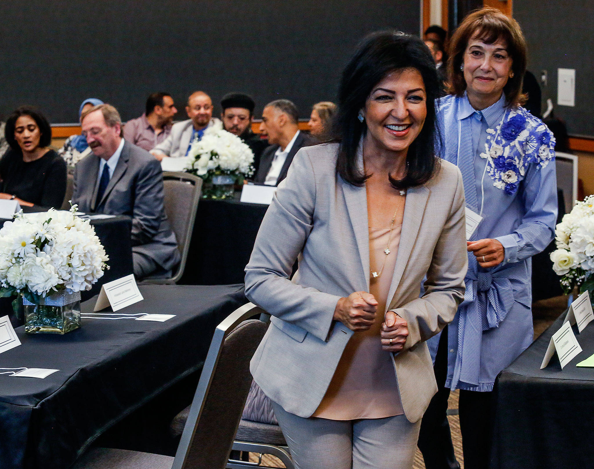 After greeting Dave Somers and his assistant, Alessandra Durham (back left) Egyptian ambassador Lamia Mekhemar, followed by Dr. Amira El-Bastawissi, spots another person of interest on the way back to her seat at the Lynnwood Convention Center Friday. (Dan Bates / The Herald)