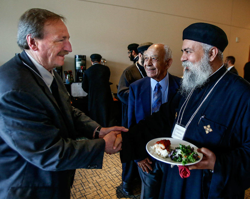 Dave Somers shakes hands with Fr. Angelos Sarkis Friday at the Lynnwood Convention Center during a break from a meeting with members of the Muslim Egyptian and Coptic Christian Egyptian communities.
