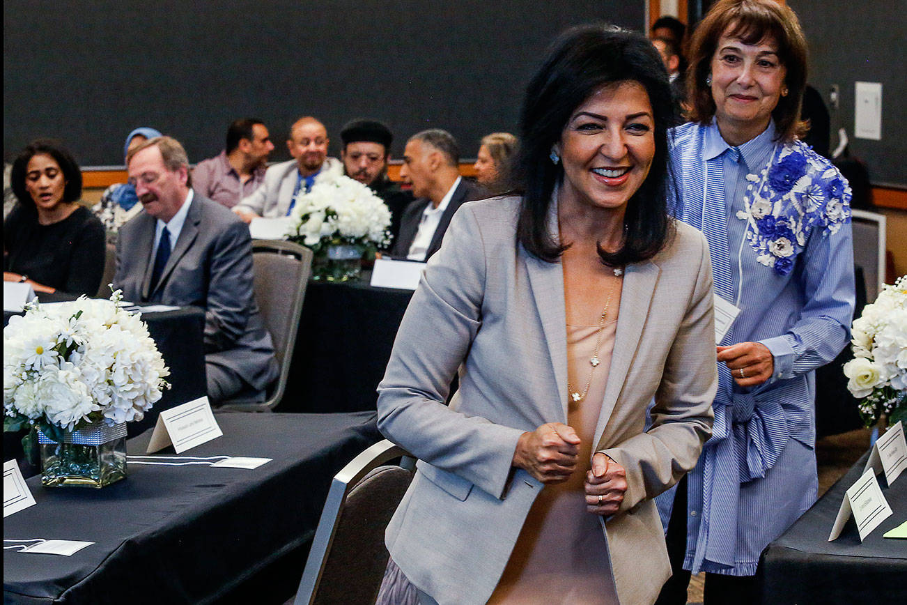 After greeting Dave Somers and his assistant, Alessandra Durham (back left) Egyptian ambassador Lamia Mekhemar, followed by Dr. Amira El-Bastawissi, spots another person of interest on the way back to her seat at the Lynnwood Convention Center Friday. (Dan Bates / The Herald)