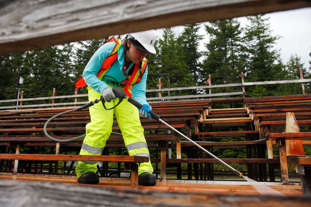 Danielle Dewberry power-washes the bleachers at the Darrington rodeo grounds in 2014. The Darrington Timberbowl Rodeo takes place this weekend at an arena in the midst of a quarter-million-dollar renovation that calls for three of the stadium’s five bleaches to be covered. (Herald file)
